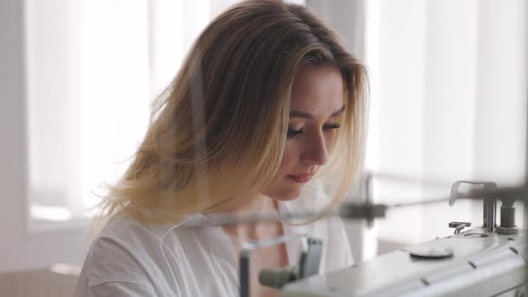 Young Beautiful Light Hair Seamstress Works Focused in the Workplace