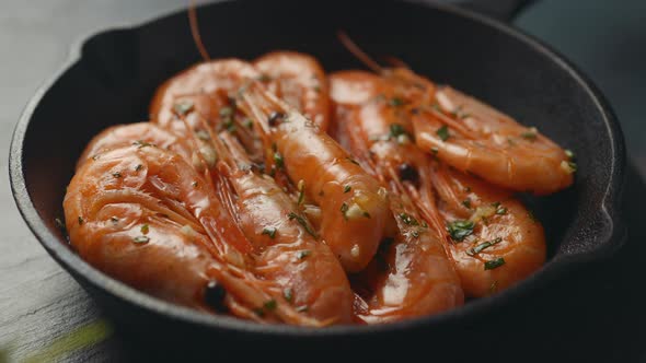 A small frying pan with shrimps in oil with spices