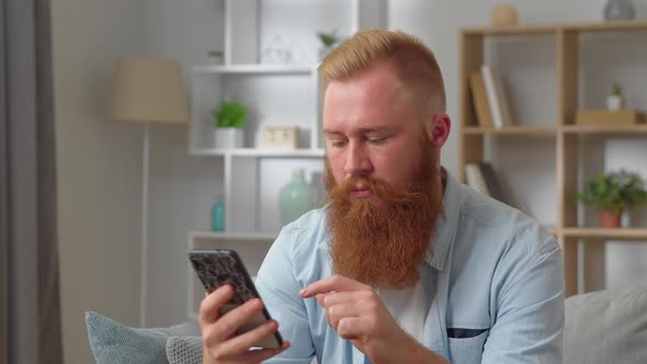Frustrated Young Redhear Man Looking at Smartphone Screen Feeling Disappointed with Received Bad alt