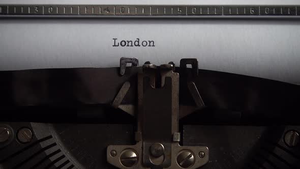 Typing city name London on a vintage typewriter. Close up. alt