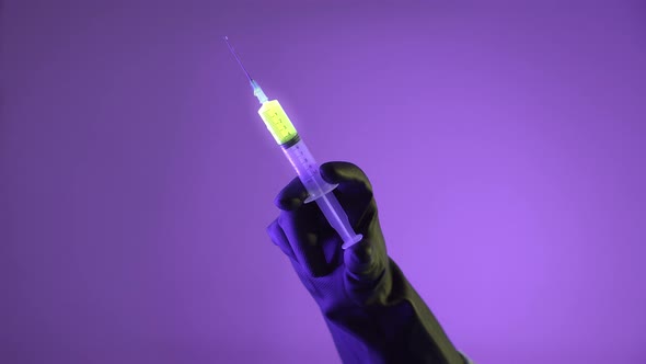 Doctor Pushes The Syringe With Glowing Liquid