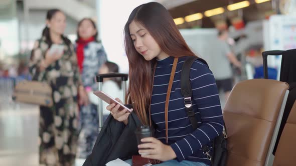 Young traveler woman use smartphone and drink coffee while waiting 