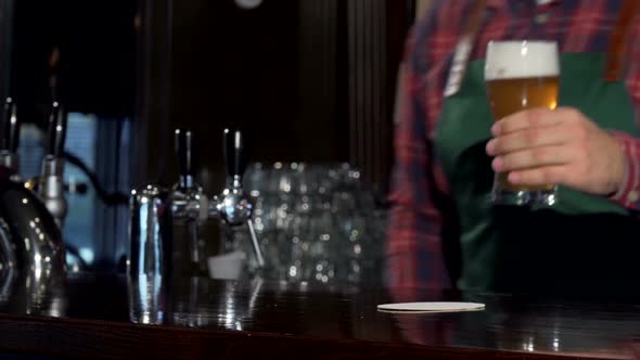 Bartender Pouring Glass of Delicious Tasty Beer at Pub, Placing It on the Counter alt