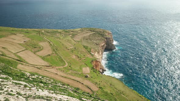 AERIAL: Rocky Steep Ta Cenc Cliffs on Windy Day near Blue Mediterranean Sea Coastline