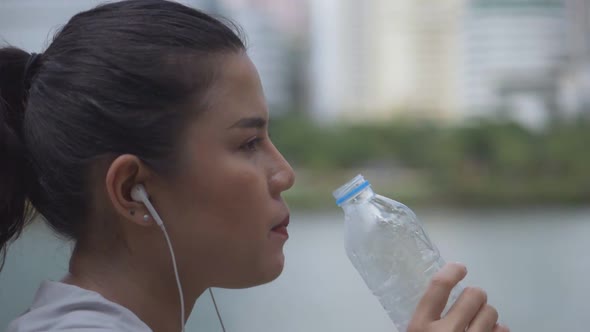 Close-up portrait young Asian woman runner drink water after running.