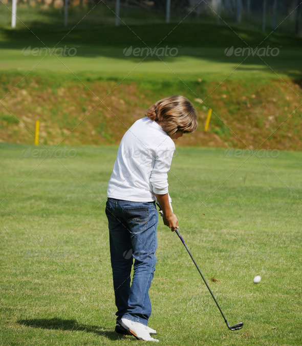 Young golfer performs a golf shot from the fairway. - Stock Photo - Images