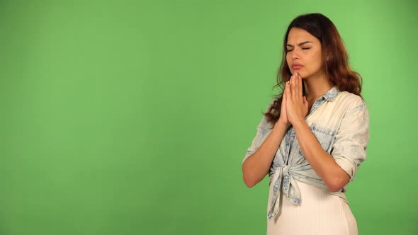 A Young Beautiful Caucasian Woman Prays with Hands Clasped Together and Eyes Closed  Green Screen