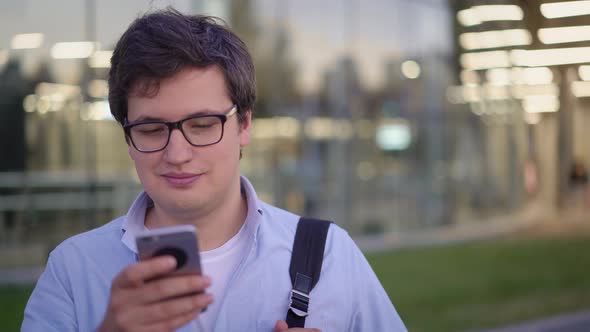 Front View Portrait of Young Man Typing in Cellphone Outdoors