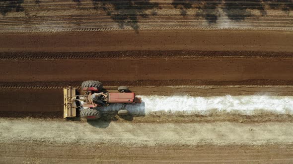 Tractor mixing fertilizer with the crop land, aerial drone shot of amending machine in the field alt