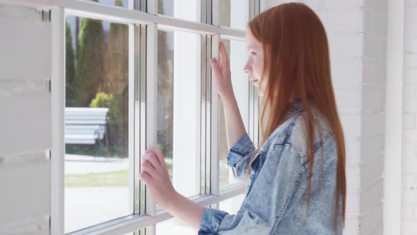 Teenage Girl Looks Out Window with Curiosity