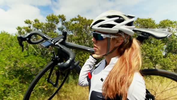 Female cyclist carrying bicycle on countryside road 4k alt