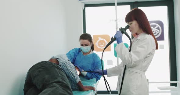 Two Surgeons in Lab Coats and an Assistant Perform Endoscopic Surgery Using alt