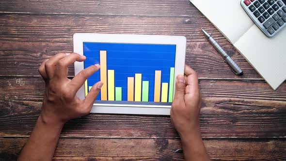 Analyzing Bar Chart on Digital Tablet at Office Desk, Using Self Created Chart 