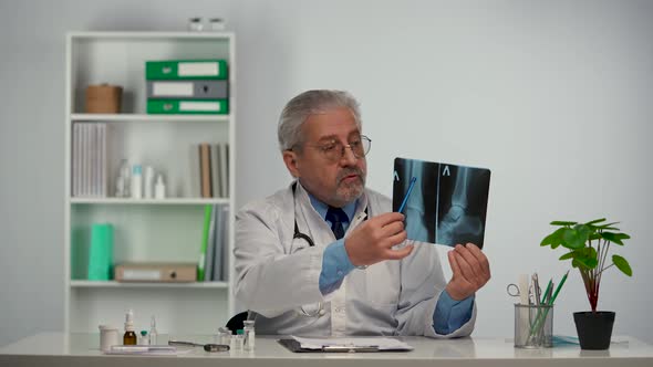 Aged Male Doctor in White Medical Coat Advises Patient By Pointing Out Disease on Picture and alt