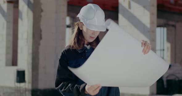 Young Female Architect Analyzing Blueprint at Site alt