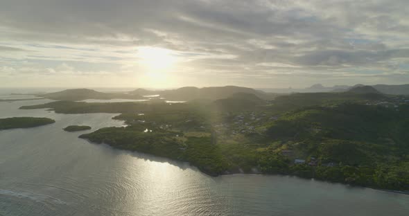 Aerial of bright sunlight over green coast and calm sea, Cap Chevalier alt