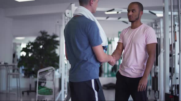 African American Guy Shakes Hands with a Caucasian Guy in the Gym Two Young Guys in the Gym People alt