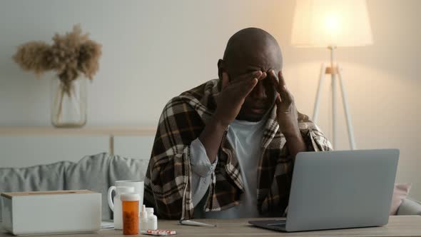 Sick African Man Rubbing Sore Eyes Sitting At Laptop Indoors alt