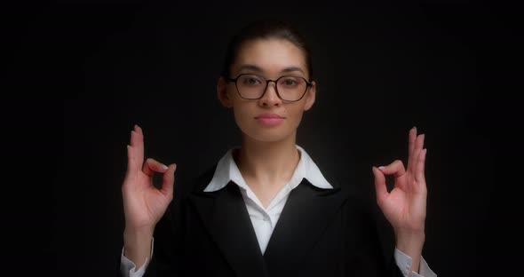 Business Woman with a Serious Face Shows the Ok Sign with Both Hands