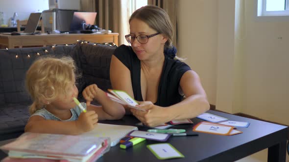 A Teacher, a Tutor for Home Schooling. a Teacher or Mom at the Table with a Little Girl alt