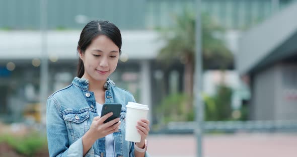 Woman use of mobile phone and holding coffee cup alt
