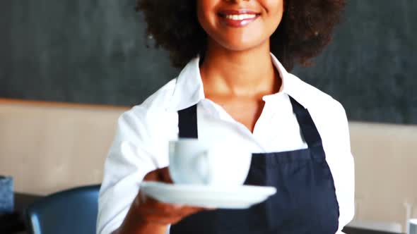 Portrait of smiling waitress holding two cups of coffee alt