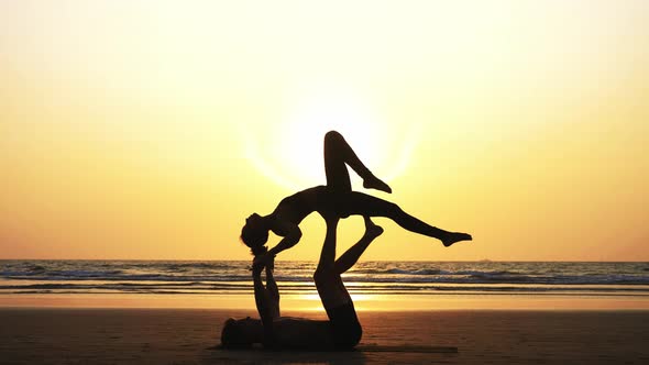 Fit Sporty Couple Practicing Acro Yoga with Partner Together on the Sandy Beach.