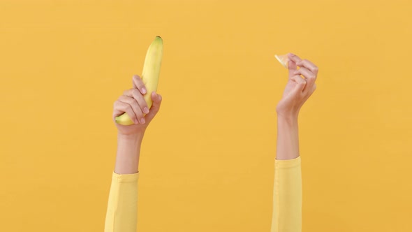 Woman hands putting condom on banana for safe sex and contraceptive concepts