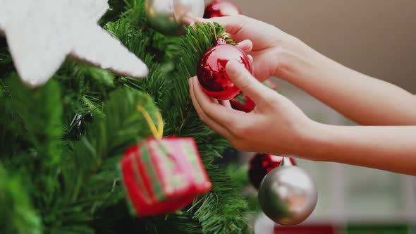 Young Asian woman holding small red balls decorate the Christmas tree.