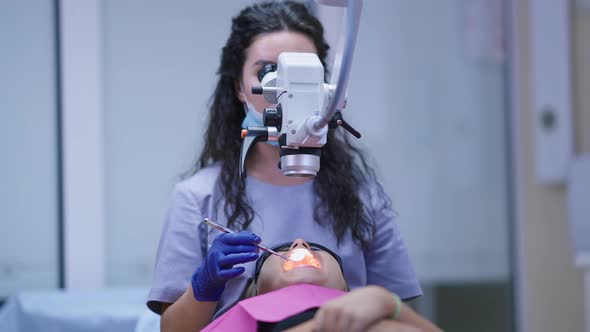 Front View Patient in Dentist Chair with Doctor Using Dental Endodontic Binocular Microscope and alt