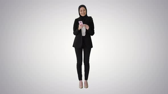 Young Muslim Woman Wearing Hijab Headscarf Walking Using Smartphone on Gradient Background alt