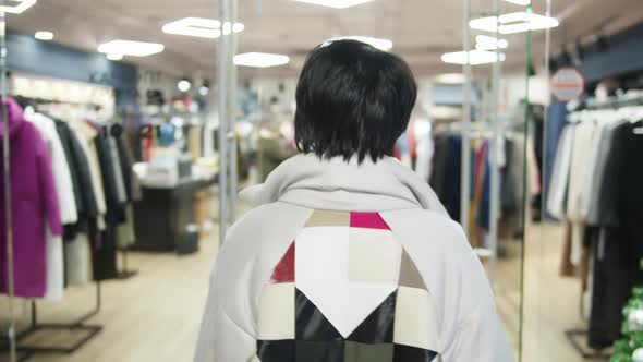 Brunette Woman in a Jacket Enters a Clothing Store Turns and Looks at the Camera