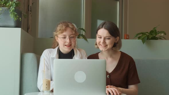 Young Girls Work Remotely in a Cafe on the Summer Terrace alt