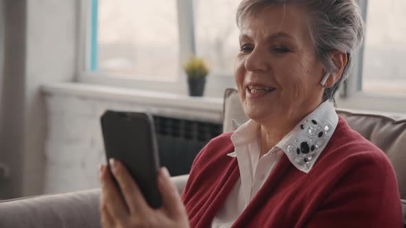 Retired Woman Is Sitting and Recording Video Message for Family at Office Using Smartphone and