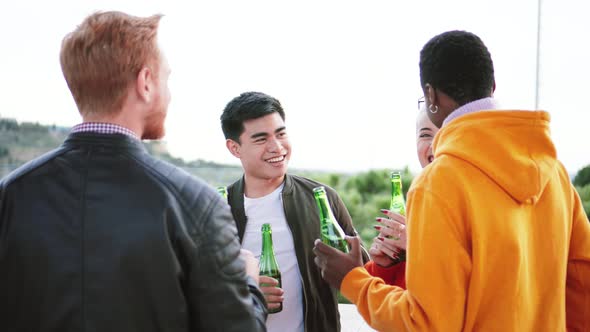 Multiethnic Young Fiends Drinking Beer Talking and Laughing in a Rooftop alt