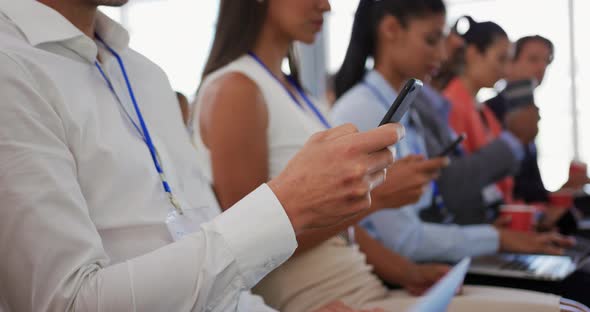 Audience at a business conference using phones and computers alt