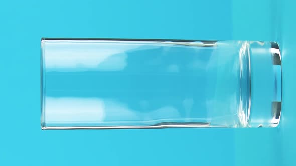 Vertical Video Closeup Shot of Milk Cold Beverage Drink Pooring Into Glass Blue Background in Studio