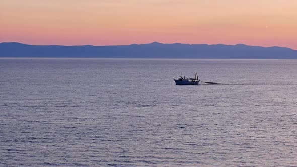 Fishing Boat Pulling Net On Calm Sea At Sunset