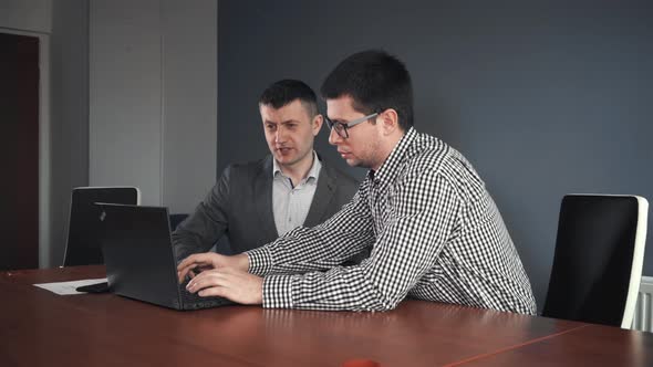 Communicating Colleagues Sharing Laptop in Office