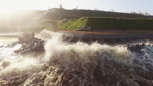 Drone Shot People Running From Big Waves Covering Them Near Sea Wall on Wonderful Sunny Day Slow alt