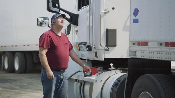 Truck driver filling up fuel tank of semi truck.  Fully released for commercial use.