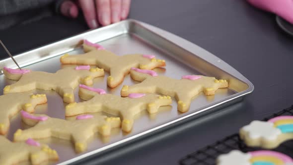 Step by step. Decorating unicorn sugar cookies with royal icing on baking sheet alt