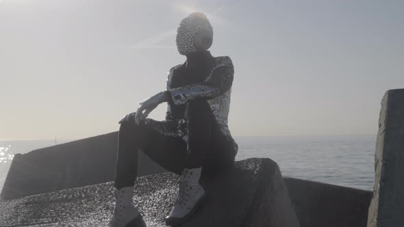 Mr Disco Man with Sparkly Face Sitting on Rocks alt