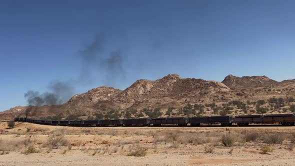 Freight Train Rides on Railroad in Desert