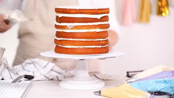 Step by step. Pastry chef stacking cake layers with buttercream frosting between to create unicorn c alt