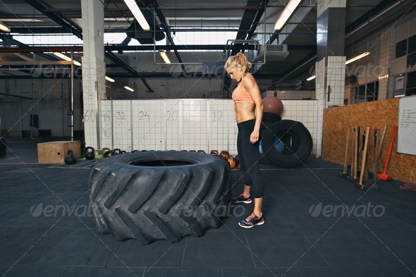 Female athlete performing tire flipping crossfit exercise - Stock Photo - Images