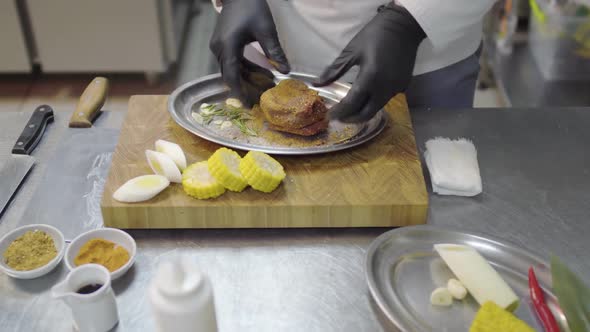 Chefs Hands in Black Latex Gloves Rubs a Piece of Veal in the Metal Plate, Marinating Meat alt