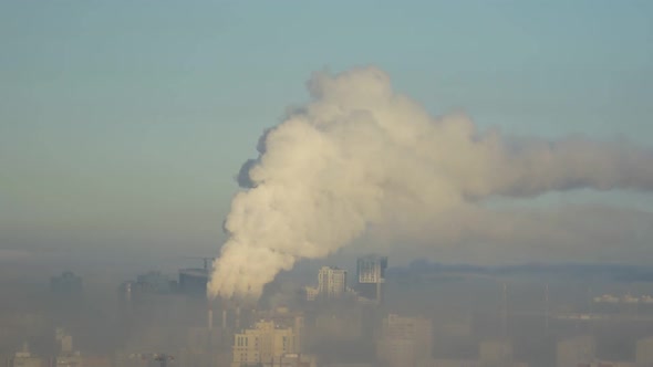 City Pipes Emit Steam Into the Atmosphere Against the City Skyline 3