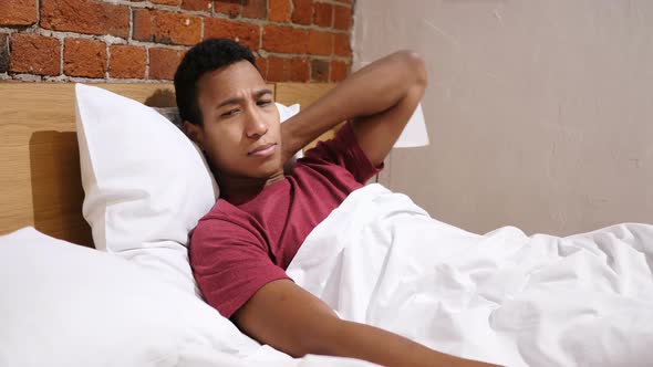 Tired African Man with Pain in Neck, Relaxing in Bed alt