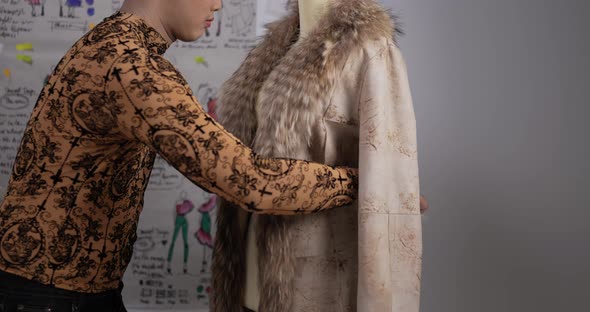 Asian fashion designer man measuring tape on mannequin model in studio. alt